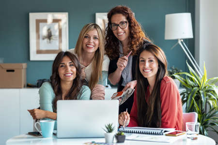Portrait of casual multiage business women working with laptops while looking at camera in the office.の写真素材