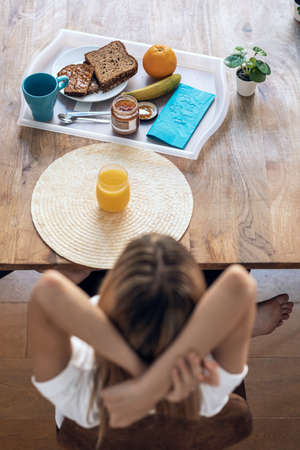 Shot of beautiful woman having healthy breakfast while streching sitting in the living room at home.の写真素材