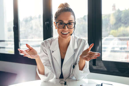Portrait of happy female doctor looking at camera while working sitting in medical consultation.の写真素材