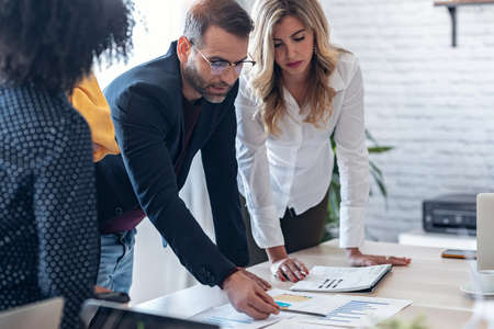 Shut of handsome business man working on new alternative energy development looking at a model of a wind turbine in modern startup.の写真素材