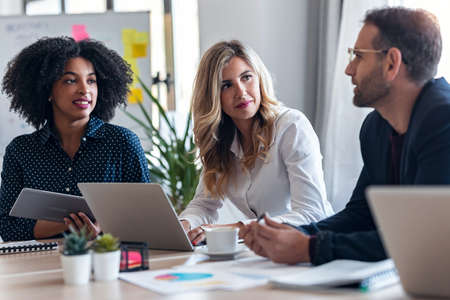 Shot of casual multiage business people working with laptops while talking of they new project together in modern startup.の写真素材