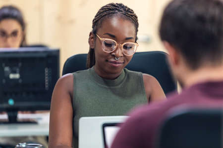 Shot of afro business woman working with laptop in a coworking place.の写真素材