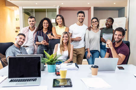 Shot of successful business team posing around laptop for presentation of work while looking at camera in a coworking space.の写真素材