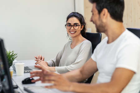 Shot of successful business team working together with computer while talking in coworking place.