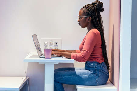 Shot of afro business woman working with laptop in a coworking place.の写真素材
