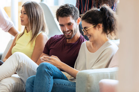 Shot of happines business team taking a break of work while talking and having fun sitting on a couch in a coworking place.の写真素材