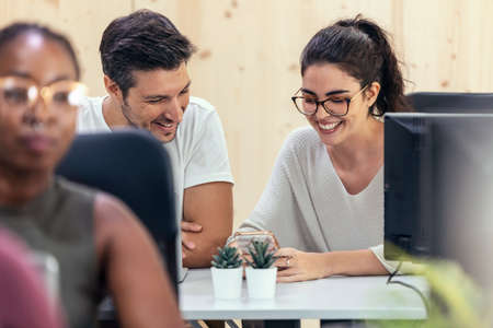 Shot of successful business team working together with computer while talking and looking smartphone in coworking place.の写真素材
