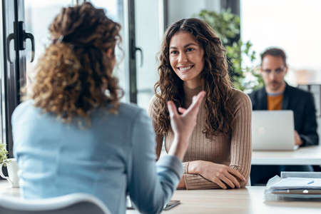 Shot of beautiful real-estate agent showing house plans on electronic tablet while talking to beautiful woman about buying the house in a real estateの写真素材