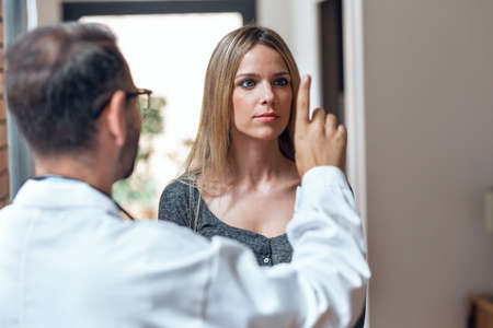 Shot of handsome male doctor ophtalmologist checking the eye vision of beautiful young woman in modern clinic.の写真素材