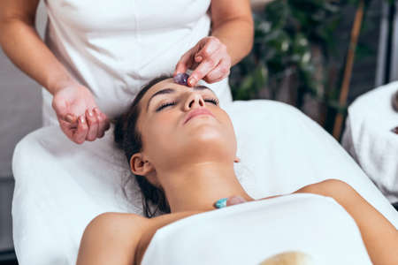 Shot of beautiful young woman having reiki healing treatment in health spa centerの写真素材