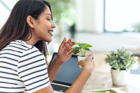 Shot of beautiful woman having a break of working while taking care of her plants in living room at home.の写真素材