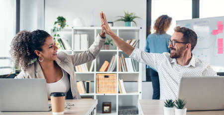 Shot of successful business multiage team celebrating standing around table in the coworking space.