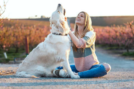 Shot of beautiful woman stroking and pampering her lovely golden retriever dog sitting on the floor...