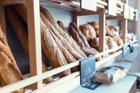 Shot of different types of delicious bread loaves placed on the shelf in a pastry shop.