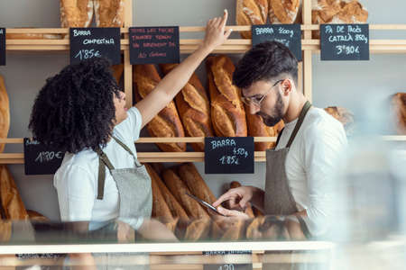 Shot of couple owners bakery working while analyzing report for order delivery with digital tablet...