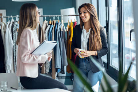 Shot of two fashion designers having a break from work while drinking coffee in the sewing workshop.の写真素材