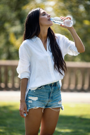 Portrait of beautiful young woman sticking her head out the car window while waving looking at the...