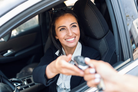 Shot of car rental agency employee giving car keys to beautiful young woman.の写真素材