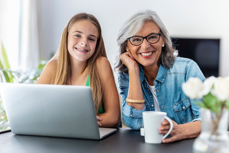Shot of happy granmother using laptop with her granddaughter at home.の写真素材