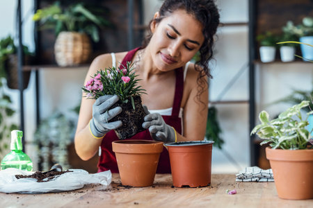 Shot of influencer woman arranging plants and flowers while recording a tutorial video with smartphone in a greenhouseの写真素材