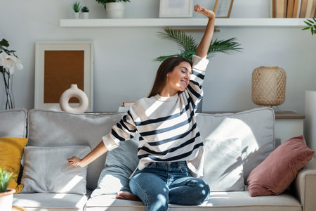 Shot of beauty young woman doing gymnastic stretches while relaxing on sofa at home.の写真素材