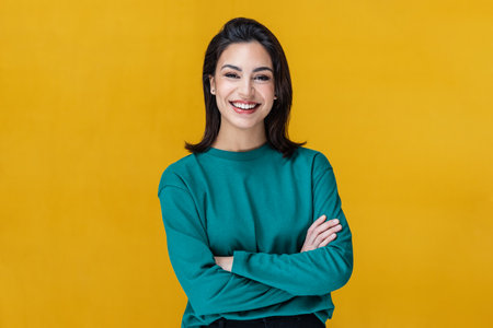 Shot of beautiful woman smiling while looking at camera on isolated on yellowの写真素材