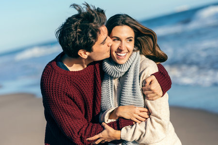 Shot of beautiful young couple in love enjoying the day in a cold winter on the beach.の写真素材