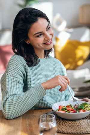 Portrait of beautiful smiling woman eating healthy salad at home.の写真素材