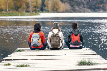 Shot of pretty family looking at the horizon sitting on a pier on the lakeの写真素材