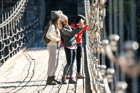 Shot of beautiful family taking pictures in the landscape while standing on a bridge in mountain forestの写真素材