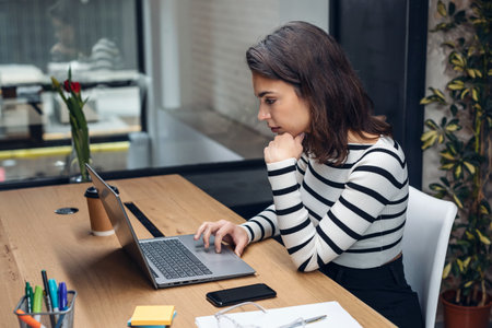 Shot of architect engineer woman working with laptop while studying the blueprints in a modern...