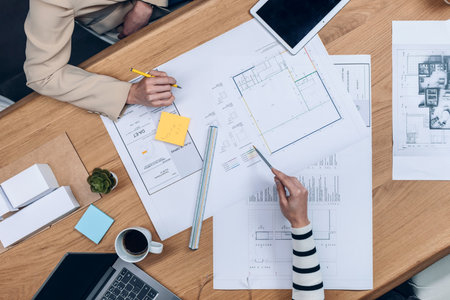 Close up of hands of architects working with blueprints of their new design business in the office.
