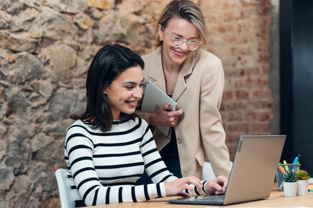 Shot of two beautiful designer women working with laptop while choosing materials on digital tablet...