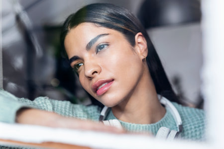 Shot of sweet young woman listening to music with headphones while looking forwards across the window at homeの写真素材
