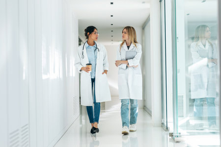 Shot of two attractive female doctors talking while consulting results on digital tablet in the hospital.の写真素材