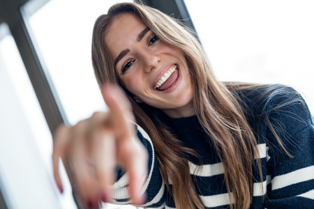 Shot of pretty young woman pointing finger at camera at home