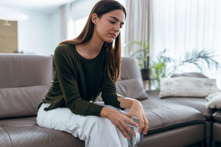 Shot of depressed young woman thinking about her problems while drinking coffee on sofa at home.の写真素材