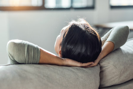 Shot of young tired woman relaxing while lying on couch in living room at home.の写真素材