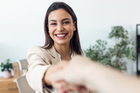Shot of smiling beautiful businesswoman handshake with a client at modern office.の写真素材