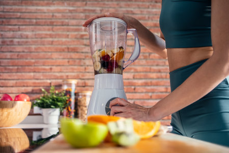 Shot of beautiful sporty woman doing healthy smoothie while listening to music in the kitchen.の写真素材