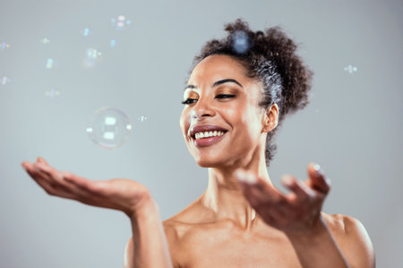 Shot of attractive mature woman playing with soap and water bubbles on isolated white