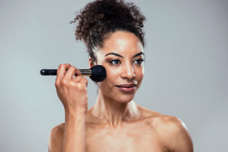 Shot of beautiful young woman doing make-up while looking at camera in isolated whiteの写真素材