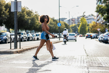 Shot of beautiful woman using smartphone while crossing a zebra crossing in the cityの写真素材