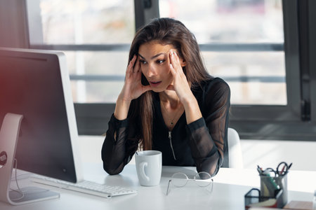 Shot of exhausted elegant business woman with headache while working with computer in the office.