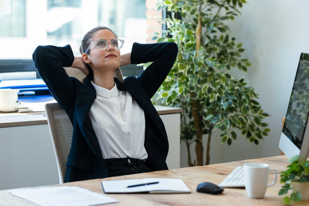 Shot of tired businesswoman stretching body for relaxing while working with computer in the office.の写真素材
