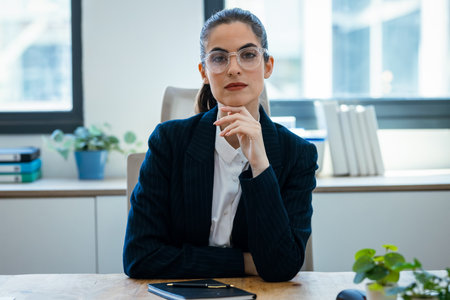 Shot of confident business woman speaking through the webcam while making a video conference from the officeの写真素材