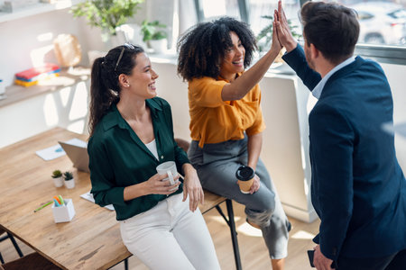 Shot of business team celebrating good job while holding up their right hands on modern startupの写真素材