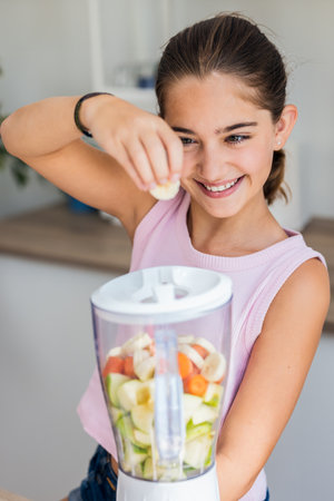 Shot of kind little girl doing a healthy fruit juice with blender in the kitchen at homeの写真素材