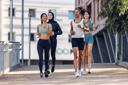 Shot of a group of four sportswomen running together through the cityの写真素材