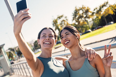 Shot of two beautiful friends with sporty clothes taking a selfie with smartphoneの写真素材